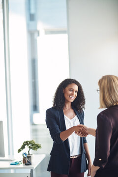 Happy business women shaking hands, meeting and greeting in an office. Confident young professional talking to a manager about a promotion or job performance. Hr congratulating an ambitious employee