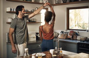 Happy, romantic and interracial couple dancing and having fun while bonding in kitchen at home....