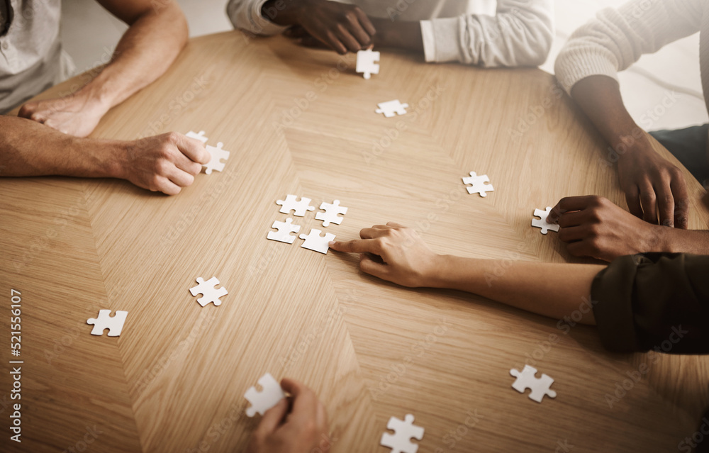 Poster Friends hands solving a puzzle in a group collaboration together as a team on wooden table indoors. Diverse colleagues using teamwork and support to help each other to find a smart solution close up