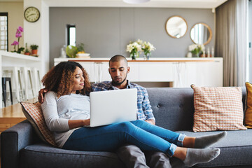 A relaxed couple on sofa watching movie on laptop or browsing internet for a romantic afternoon indoors. Casual, young and in love boyfriend and girlfriend bonding while searching the web on laptop