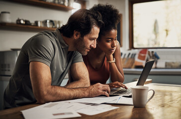 Couple with a laptop doing finance paper work, paying debt insurance loans or online ebanking...
