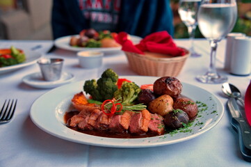 Closeup of duck's breast with potatoes and vegetables on the table in restaurant