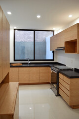 Modern wooden kitchen, with black or gray granite bar, with tile backsplash, light floor.