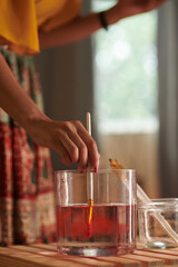 Close-up image of female artist cleaning brush from red paint