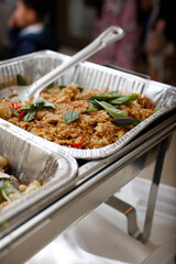 A closeup view of a chafer dish filled with savory entrees, seen at a local catered event.