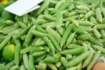 A view of a large pile of sugar snap peas, on display at a local farmers market.