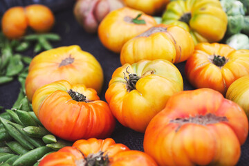 A view of a table full of rustic heirloom tomatoes, on display at a local farmers market.