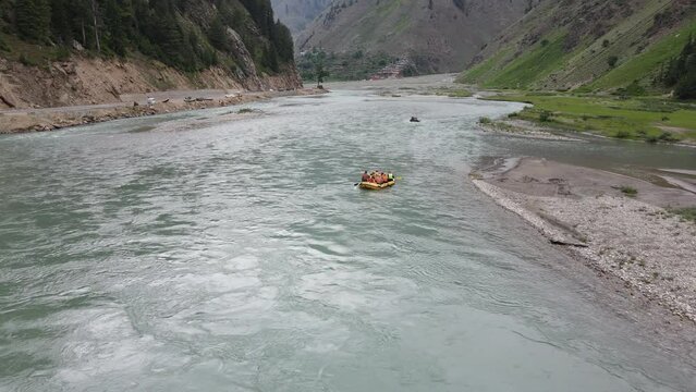Drone flying over Kunhar river while tourists enjoy river rafting in the boat, Kunhar is located in Kaghan valley (Pakistan). This valley is a popular summer destination for domestic tourists. 