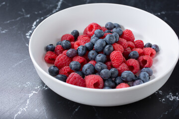 A view of a bowl of berries, featuring blueberries and raspberries.
