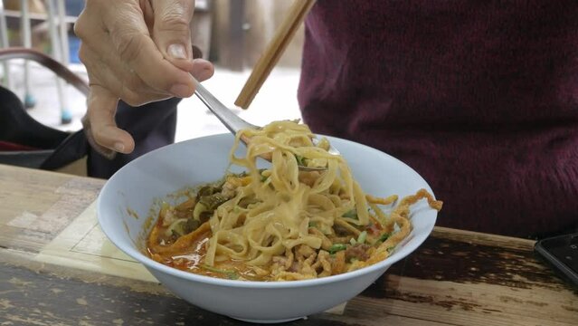 man while eating famous traditional khao soi in lana chiang mai yellow spicy taste noodle soup style.
