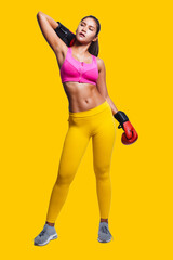Asian woman with boxing gloves in fitness outfit while look up, isolated on yellow background.
