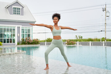 Pretty African American woman playing yoga for relax and healthy on sport club and pool