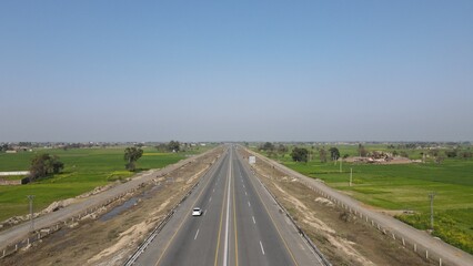Naklejka premium An aerial image of Lahore-Sialkot Motorway on a clear sunny day with some moving vehicles, Punjab Province, Pakistan. 