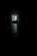 A window at the end of a dark, unlit corridor. Dark dark dark corridor of an abandoned building