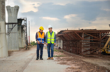 Engineer and builders in hardhats discussing on infrastructure construction site, Engineer and...