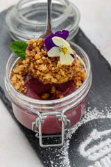 panna cotta with nuts decorated with a ticket in a transparent jar with a spoon
