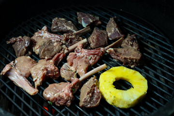 meat and pineapple are grilled on charcoal
