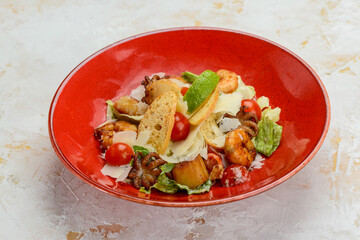 salad with seafood in a red plate on a white background
