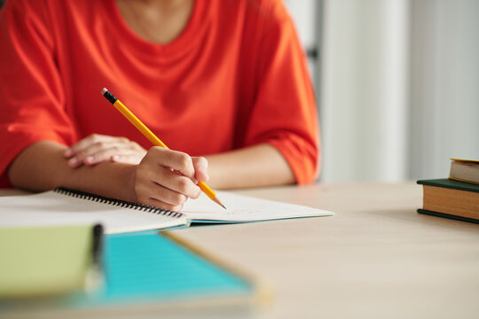 Closeup image of schoolgirl writing in textbook with sharp pencil