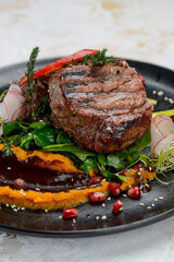 grilled meat steak on a black plate with salad and sauce macro photo
