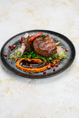 grilled meat steak on a black plate with salad and sauce, vertical photo
