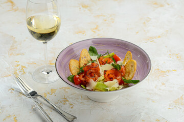 salad with salmon and bruschetta in a serene plate on a white background with a glass of wine
