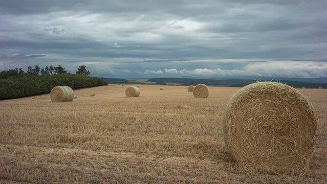 The bale of straw is on the field. Clouds run across the sky.