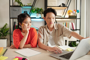 School kids attending online class, they are sitting at desk with opened laptop