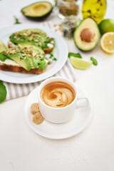 Freshly made Avocado and cream cheese toasts on a white ceramic plate and ingredients