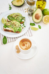 Freshly made Avocado and cream cheese toasts on a white ceramic plate and ingredients