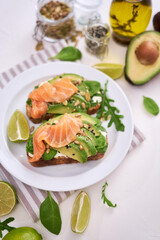 Freshly made Avocado, salmon and cream cheese toasts on a white ceramic plate