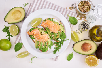 Freshly made Avocado, salmon and cream cheese toasts on a white ceramic plate