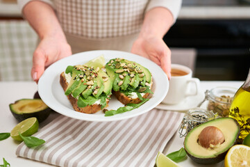 Freshly made Avocado and cream cheese toasts on a white ceramic plate and ingredients