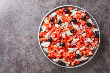 Spanish appetizer salad of salted cod, fresh tomatoes, onions and black olives close-up in a plate on the table. horizontal top view from above