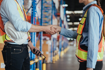 Close up hands of warehouse workers handshake for partnership in logistic center, Industrial...