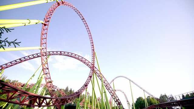 Roller coaster Ride against blue sky. Roller coaster in the amusement park. Cheerful entertainments in park of attractions