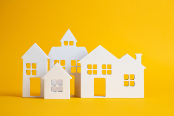 Fototapeta premium Miniature houses on yellow background. Building blocks arranged in row.