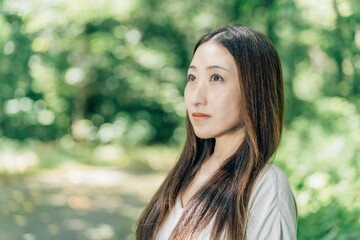Naklejka premium 森の中にいるロングストレートヘアのアジア人女性 
