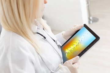 Doctor holding a digital tablet with x-ray of spine skeleton. Red pain on the bones.