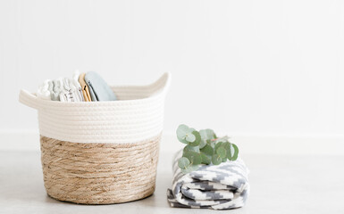 wicker basket for towels and linen on  background of white wall room and eucalyptus branch