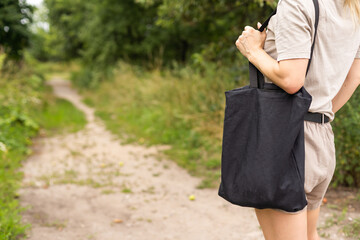 Girl is holding black cotton eco tote bag, design mockup