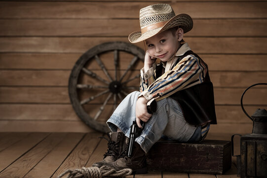Portrait of a small child pretending to be a cowboy. Dreamy boy in a stylish suit.