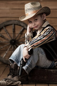 Portrait of a small child pretending to be a cowboy. Dreamy boy in a stylish suit.