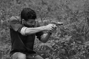 Detective with a gun in the forest in black and white