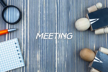 MEETING - word (text) on a wooden background, notepad and pen with calculator. Business concept (copy space).