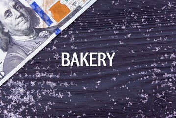 BAKERY - word (text) on a dark wooden background, money, dollars and snow. Business concept (copy space).