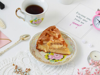 There is a cup of coffee and a piece of homemade apple pie on a white table background