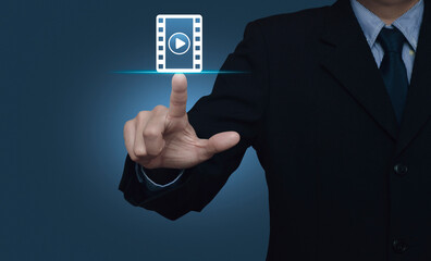 Businessman pressing play button with movie flat icon over light blue background, Business cinema online concept