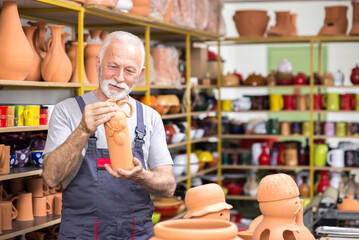 Senior craftsman potter making pottery in his workshop