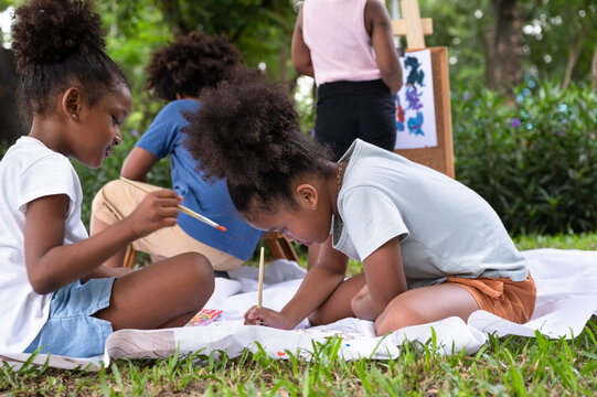 African American kid girl with friend painting in the park	